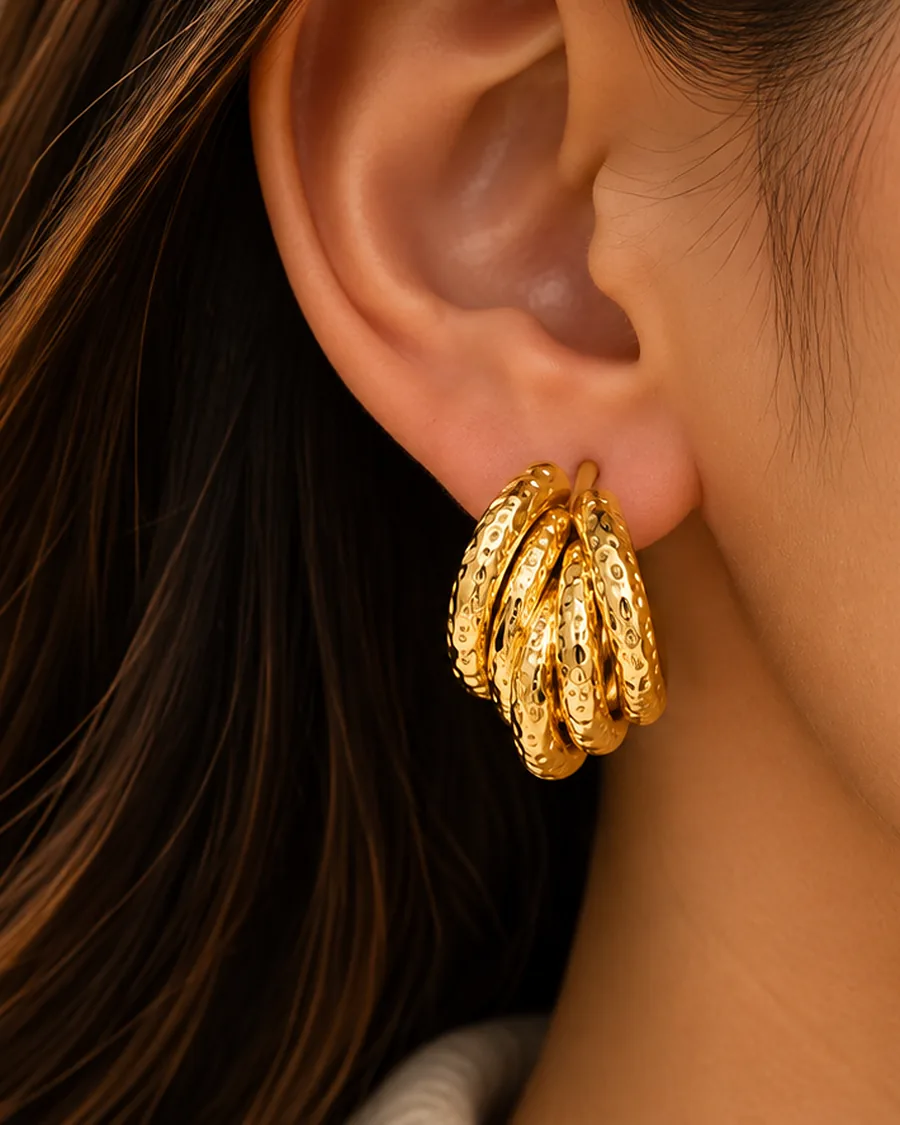 The hammered Aura hoops worn in one ear, hair swept back